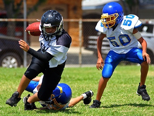 three boys playing football with athletic mouthguards