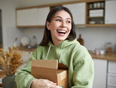 Woman in green hoodie smiling over mailed package