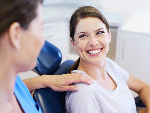 woman in exam chair with assistants hand on shoulder