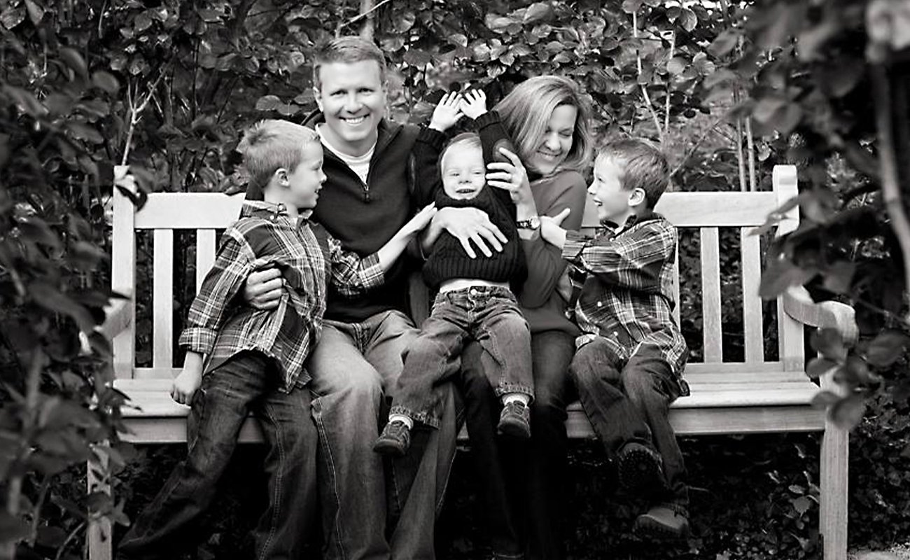 Skokie dentist with his family sitting on bench laughing and smiling