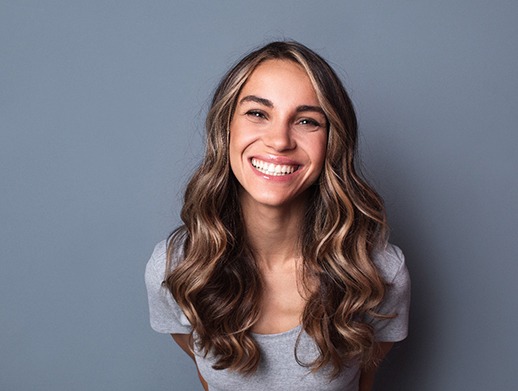 Woman with long brown hair in gray shirt smiling