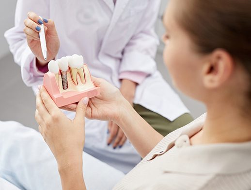 A dentist showing a patient a model of a dental implant