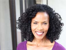 Woman with curly hair and purple shirt smiling