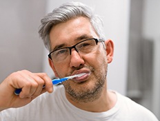 Woman maintaining her dental implants in Skokie by brushing teeth