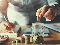 Person dropping coins into a jar