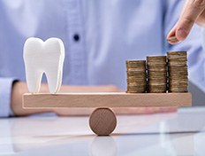 Tooth and a pile of coins on a seesaw