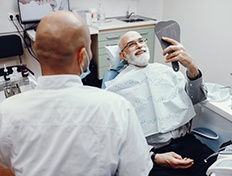 dental patient admiring his new smile in the mirror 