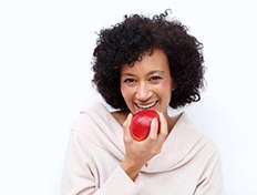 woman biting into a red apple