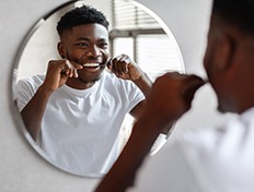 Man smiling while flossing teeth at restaurant