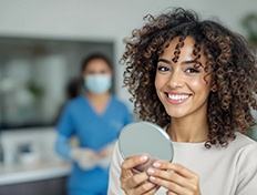 Woman smiling while holding small mirror