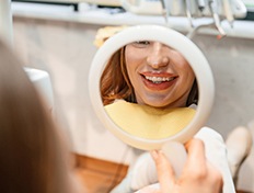 Patient with clear aligners smiling at reflection in mirror