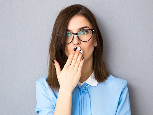 woman with black and white nails covering smile before Invisalign treatment