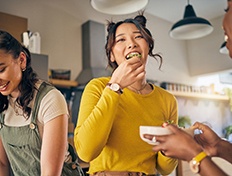 Woman smiling while eating with friends in kitchen