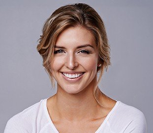 woman in white smiling at camera after preventive dentistry appointment