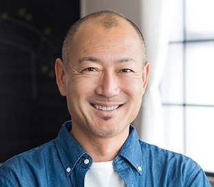 man in button down smiling at camera after replacing missing teeth