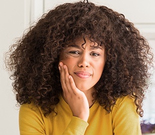 woman in pain holding cheek before restorative dentistry appointment