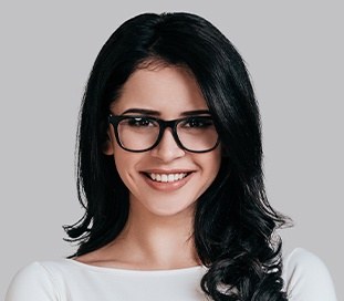 woman with glasses smiling after cosmetic dentistry appointment