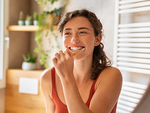 Woman smiling while brushing her teeth