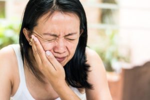 woman with toothache in Skokie holding her face in pain