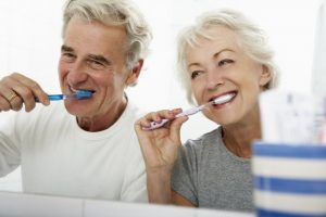 elderly couple brushing their teeth together 