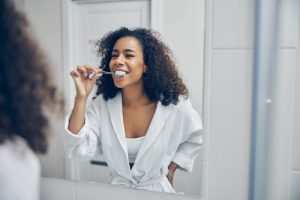 woman brushing her teeth to extend the lifespan of veneers in Skokie 