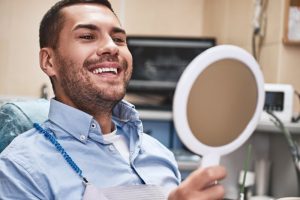 male dental patient looking in mirror