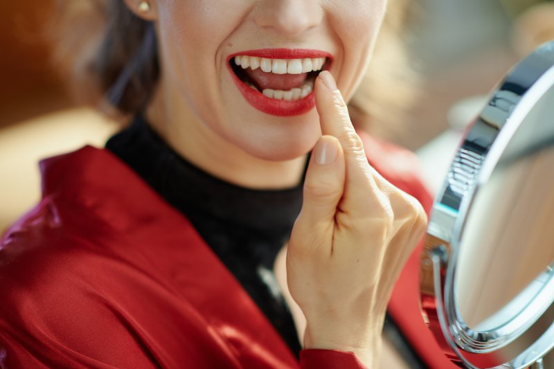 Woman checking teeth in mirror.