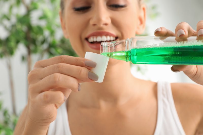 Smiling woman pouring mouthwash