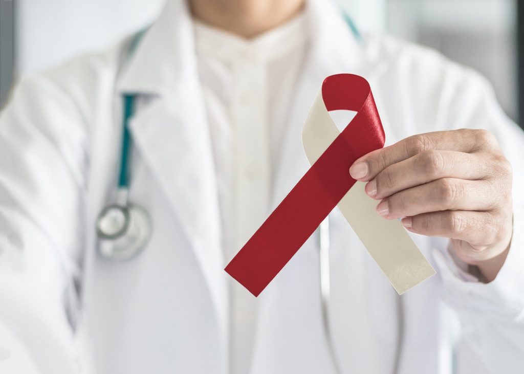 Doctor holding red and white ribbon for oral cancer awareness month