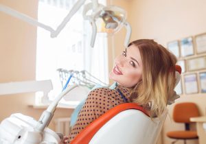 Woman with polka dot shirt in dentist's chair smiling