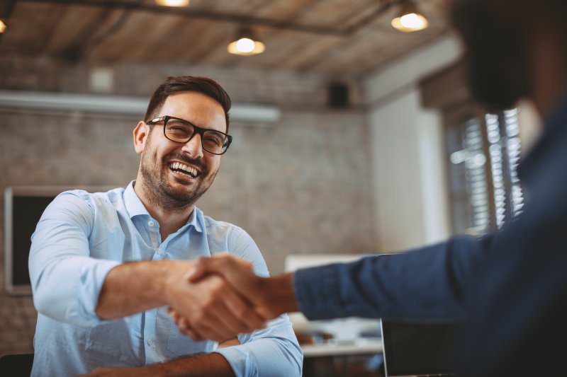 Patient shaking hands with a client after cosmetic dentistry