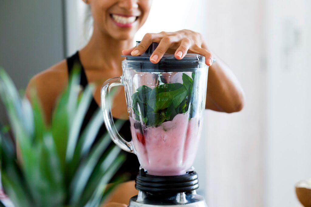 Woman blending fruit and spinach for smoothie